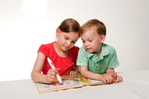 Kinder mit Ting-Stift und Buch.