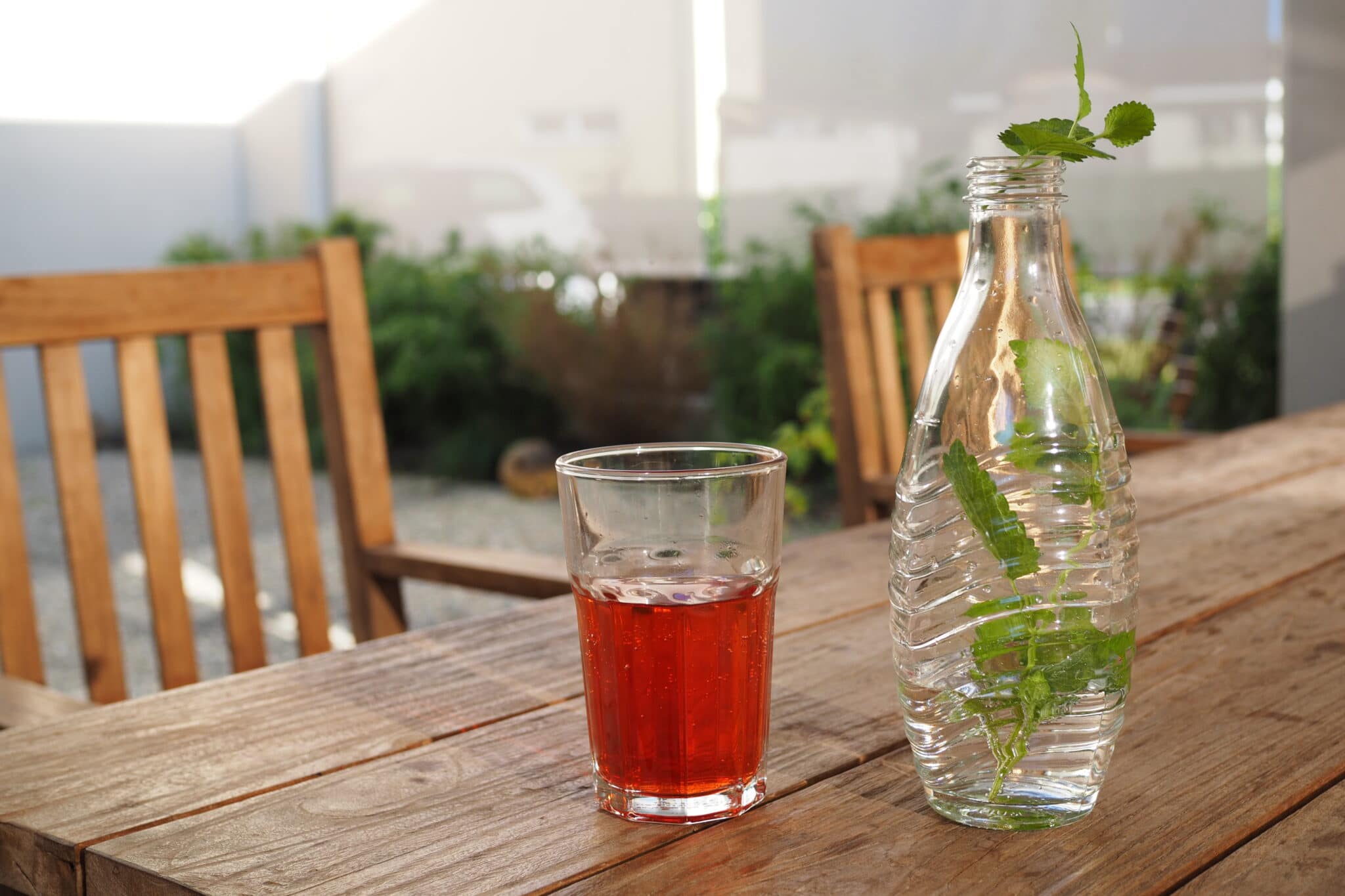 Sommer-Sprudler - Glas und Flasche auf dem Gartentisch