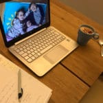 Aufgeklappter Laptop auf dem Tisch mit Kaffee und Schreibblock daneben