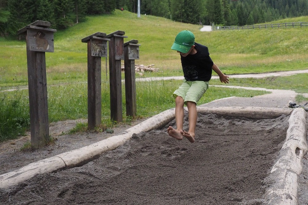 Junge macht Weitsprung im Sand in Tirol