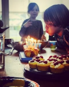 Kind bläst Kerzen auf Kuchen aus