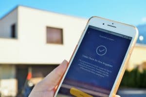 Hypotheken-App auf iPhone mit Haus im Hintergrund
