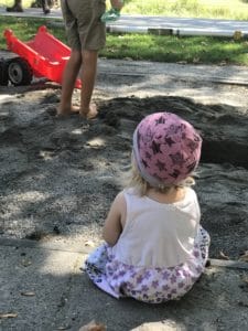 Kind sitzt am Sandkasten