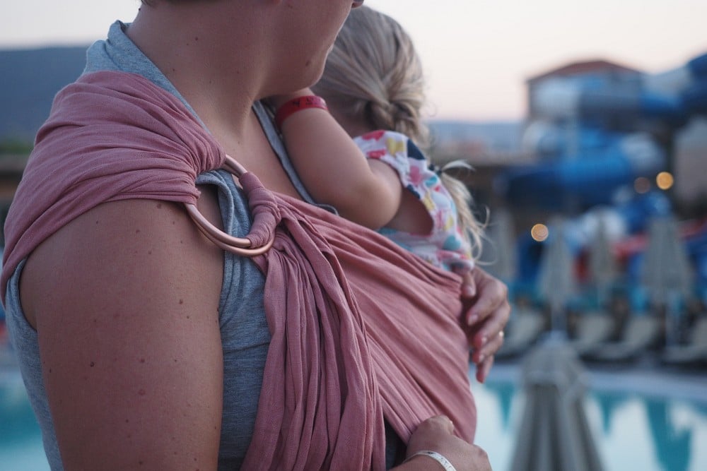 Mama trägt Mädchen im Mariblum Ring Sling aus Hanf