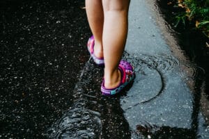 Mädchen mit Crocs auf nasser Strasse