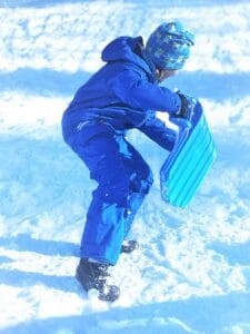 Junge spielt mit Rutscher im Schnee