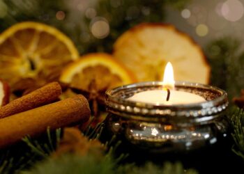 Kerze im Adventsgesteck mit getrockneten Orangen und Zimtstangen