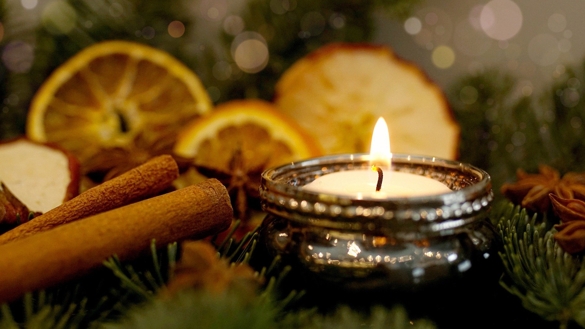 Kerze im Adventsgesteck mit getrockneten Orangen und Zimtstangen